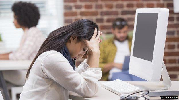 Woman with her head in her hands in front of her computer