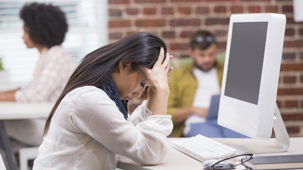 Woman with her head in her hands in front of her computer