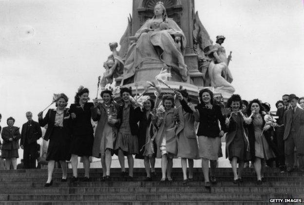 Women waving flags outside Buckingham Palace on VE Day, 8 May 1945