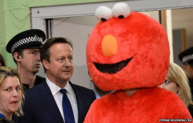 Prime Minister David Cameron (left) walks past a man dressed as Elmo during the General Election count at the Windrush Leisure Centre in Witney.