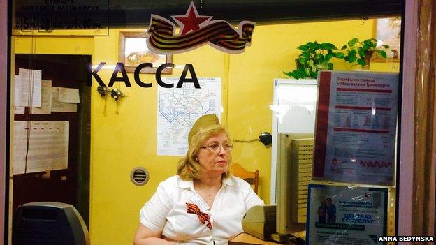 Cashier at the Moscow underground wearing a green oblong hat