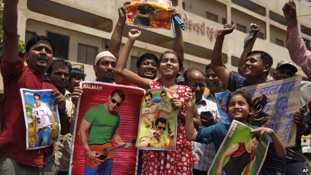 Indian fans hold posters displaying portrait of Bollywood actor Salman Khan as they celebrate in Ahmadabad, India, Friday, May 8, 2015.