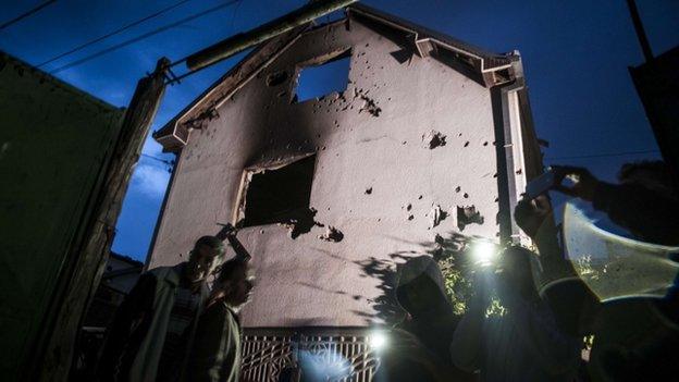 People stand near a destroyed houses following clashes between Macedonian police and an armed group in Kumanovo on 10 May 2015.