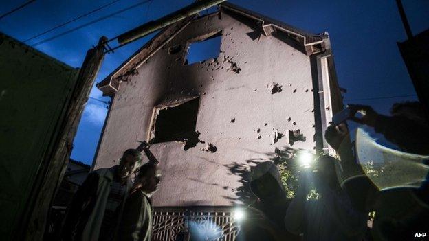 People stand near a destroyed houses following clashes between Macedonian police and an armed group in Kumanovo on 10 May 2015.