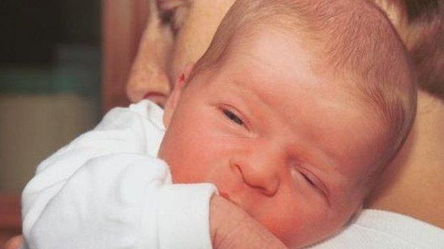 A woman holds a small baby