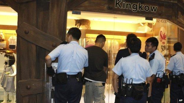 In this Sunday, May 10, 2015 photo, police officers watch a wild boar, top, at a children’s clothing store at a mall in Hong Kong.