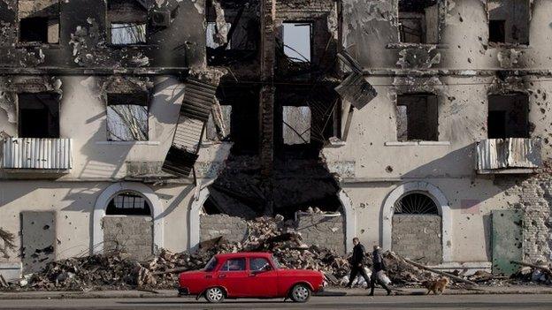 People pass by a destroyed building in Vuhlehirsk, Ukraine, 9 March 2015