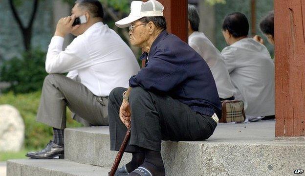 An elderly Korean man sitting alone on some steps