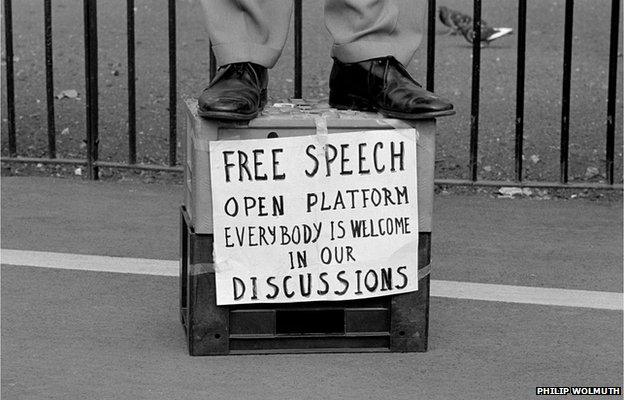 A speaker standing on a milk crate, with a sign advocating free speech, addresses a crowd at Speakers Corner, Hyde Park, London, 1993