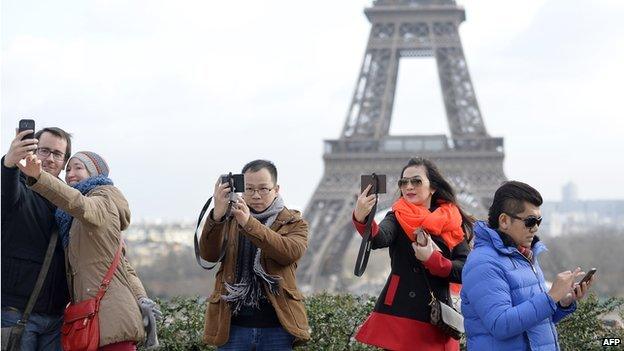 People taking selfies in front of the Eiffel Tower in Paris