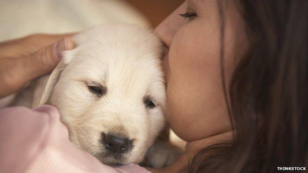 A woman cuddles a puppy