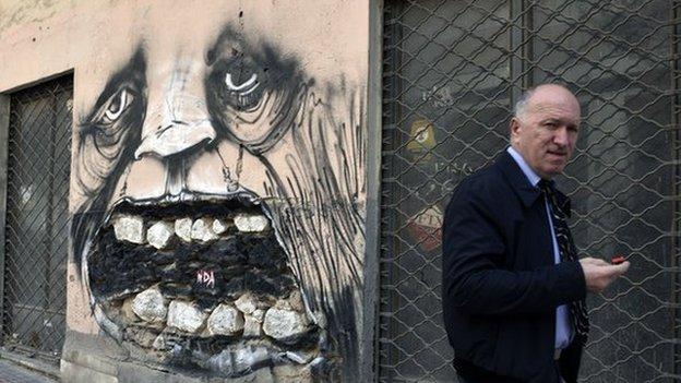 A man walks past abandoned businesses in central Athens in April 2015