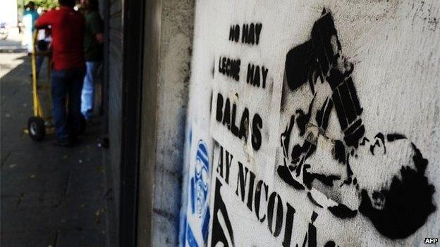 A stencil that reads 'There's no milk, there are bullets' on a wall in Caracas