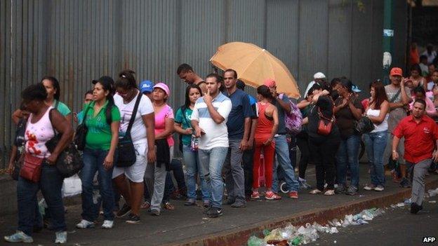 People queue outside a supermarket in Caracas