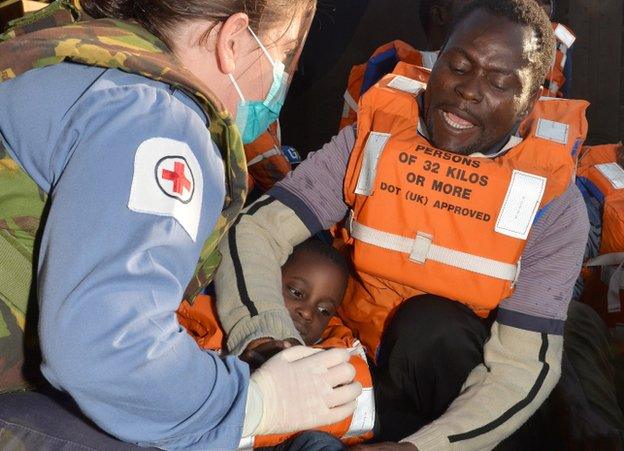 Royal Navy medical assistant cares for a four-year-old migrant who has just been rescued