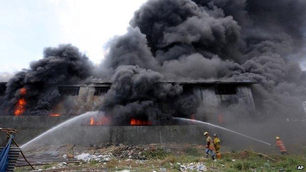 Firemen train their hoses at the burning Kentex footwear factory at Valenzuela city, a northern suburb in Manila, Philippines, Wednesday, May 13, 2015