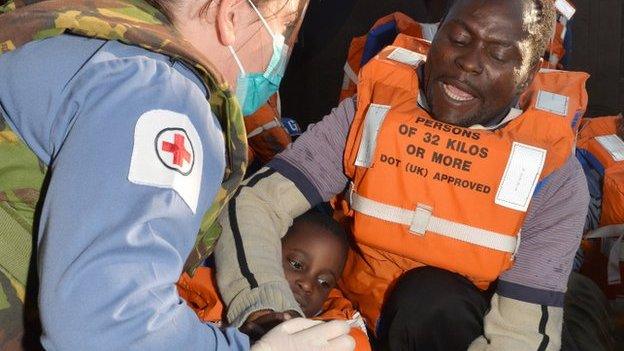 Royal Navy medical assistant cares for a four-year-old migrant who has just been rescued