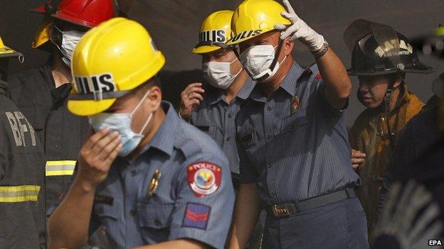 Filipino policemen wearing facemasks inspect a burnt warehouse following a fire in Valenzuela city, east of Manila, Philippines, 13 May 2015