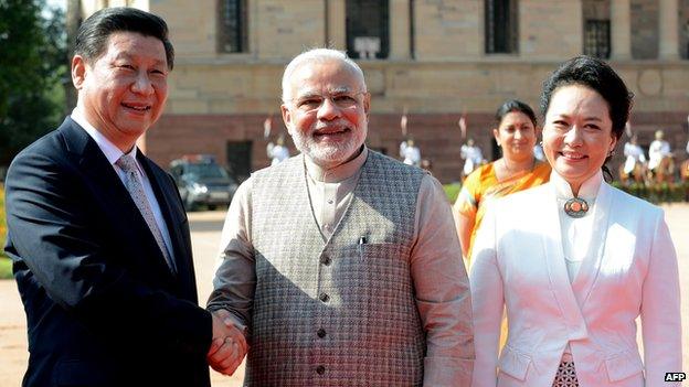 Chinese President Xi Jinping (L) shakes hands with Indian Prime Minister Narendra Modi (C) as Xi's wife Peng Liyuan looks on during a welcoming ceremony at the Presidential palace in New Delhi on 18 September 2014.