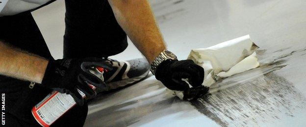 An engineer attempts to clean tyre marks from the garage