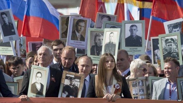 Vladimir Putin with a picture of his father in uniform