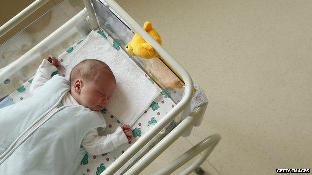 A baby in a hospital cot