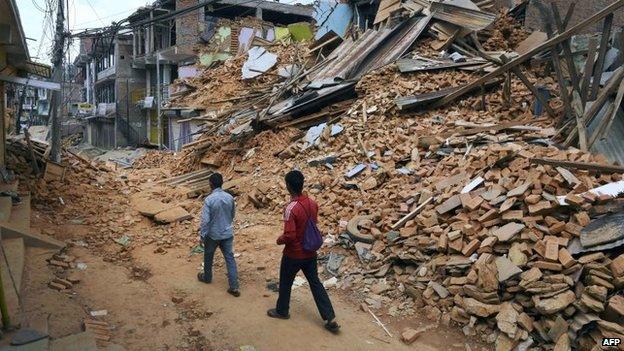 Nepalese residents walk past destroyed buildings after two earthquakes in three weeks shook the country in Chautara in north-eastern Nepal on May 13, 2015,