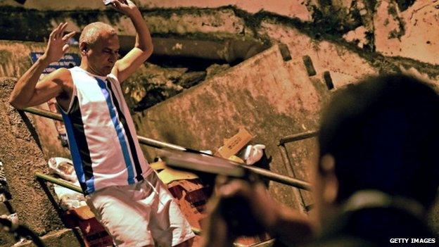 A military policeman aims his gun as a man walks past with his arms up during a protest in a favela near Copacabana in Rio de Janeiro, Brazil on April 22, 2014.