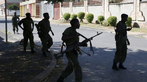 Soldiers, loyal to President Pierre Nkurunziza, walk past the body of a soldier, loyal to the coup leader, at a street in Bujumbura, Burundi, on 14 May 2015