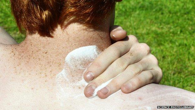 A man protecting the back of his neck with sunscreen