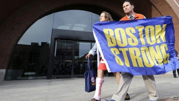 Carlos Arredondo holds a "Boston Strong" banner as he leaves the Moakley Federal court with his wife Melida