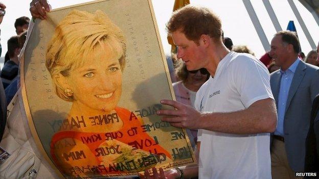 Prince Harry looking at a poster of his late mother, Princess Diana