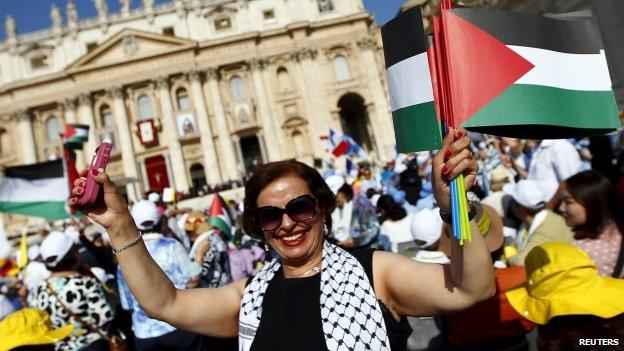 A woman attending the canonisation ceremony in the Vatican City waves Palestinian flags (17 May 2015)