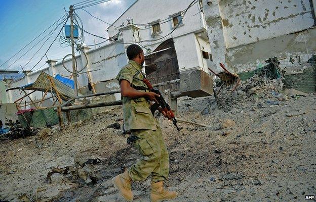 A solder walks past at the scene of a car bomb attack and armed raid by al-Shabab militants on the Maka al Mukarama hotel in Mogadishu 27 March 2015.