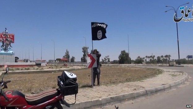 A screen grab from IS video uploaded on 18 May 2015 shows an IS fighter hanging the group's flag in a street of Ramadi, the Iraqi capital of Anbar province, a day after the city was captured by IS.