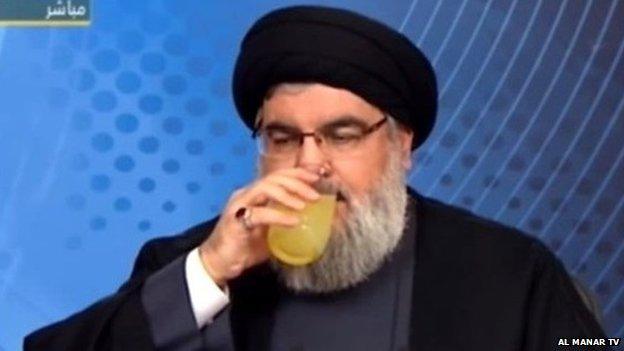 Hassan Nasrallah drinking from a glass during a TV speech