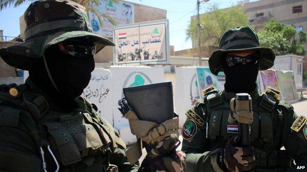 Iraqi fighters of the Shiite militia Asaib Ahl al-Haq (The League of the Righteous) stand guard outside their headquarters on 18 May 2015 in the Iraqi mainly Shiite southern city of Basra