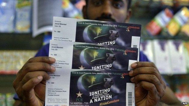 In this photograph taken on May 16, 2015, a Pakistani shopkeeper poses with tickets for the forthcoming Pakistan and Zimbabwe cricket series at a shopping mall in Lahore.