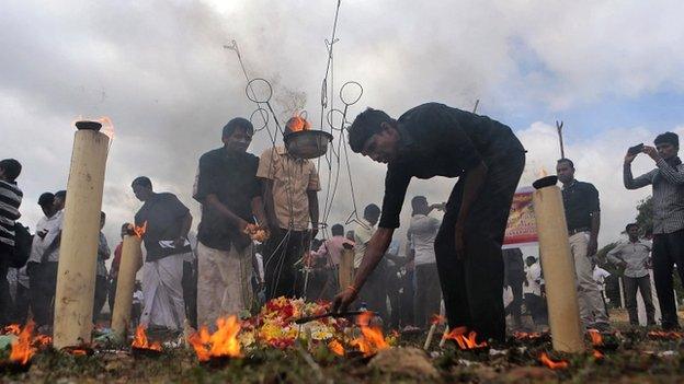 Sri Lanka's ethnic Tamil political activists offer flowers at a makeshift monument, where thousands of people were killed in fierce fighting between the army and Tamil Tiger rebels, in Mullivaikkal. May 18, 2015.