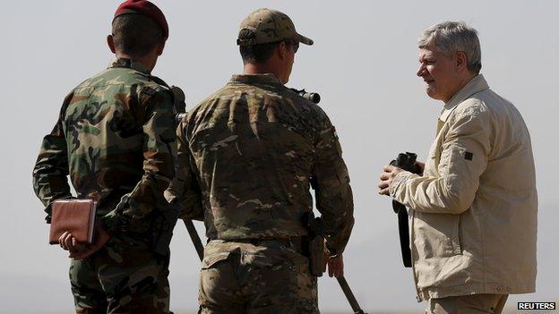 Canada's Prime Minister Stephen Harper (R) looks out towards Islamic State positions while visiting an advise and assist mission