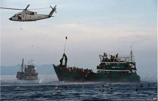 This file photo taken on 14 May 2015 shows Rohingya migrants swimming to collect food supplies dropped by a Thai army helicopter after they jumped from a boat (R) drifting in Thai waters off the southern island of Koh Lipe in the Andaman sea.