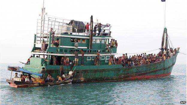 Acehnese fishermen (L-in boat) help Rohingya migrants in their boat off the coast near the city of Geulumpang in Indonesia"s East Aceh district of Aceh province before being rescued on 20 May 2015