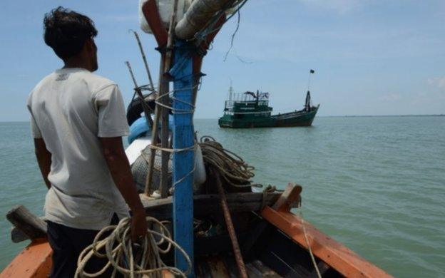 A local fishermen (L), one of many who earlier in the day helped rescue migrant Rohingya from Myanmar and Bangladesh, looks at their abandoned ship off the coast near the city of Geulumpang in Indonesia"s East Aceh district of Aceh province on May 20, 2015.