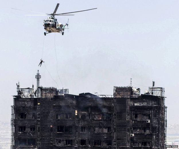 A rescuer descends from a helicopter over the roof of a burnt multi-storey residential building in Baku, Azerbaijan, 19 May 2015