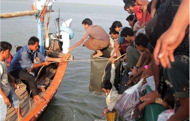 Acehnese fishermen (L) help transfer Rohingya migrants (R) from their boat off the coast near the city of Geulumpang in Indonesia"s East Aceh district of Aceh province on May 20, 2015.