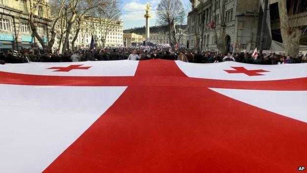 Georgians carry a giant national flag during an opposition rally in Tbilisi