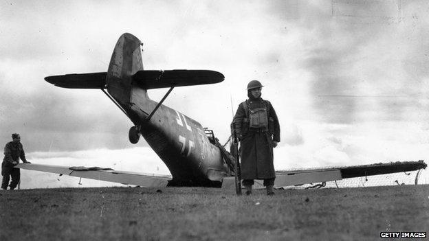 A British soldier guarding a German Messerschmitt fighter plane, which was intercepted over the English Channel and shot down by a Spitfire patrol, 27 October 1940