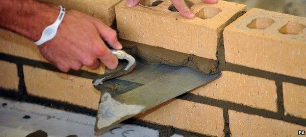 Close up of the hands of a trainee bricklayer, laying bricks