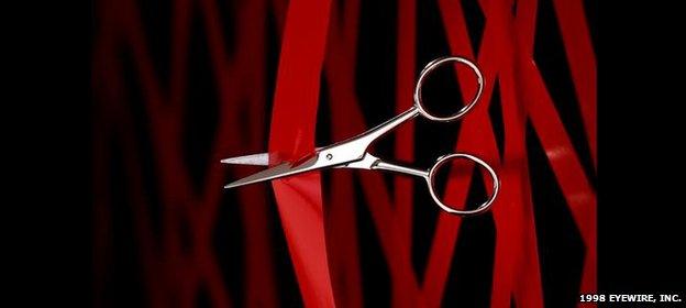 Scissors cutting red tape