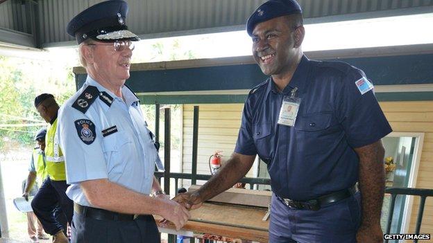 Bernadus Groenewald (L) greets a police officer during Fiji's 2014 election